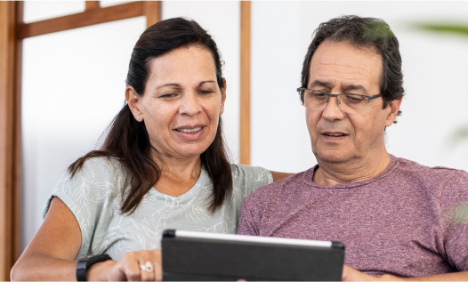 Happy South Asian American couple sitting on a sofa using a digital tablet at home
